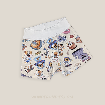A pair of children's boxer briefs by WunderUndies, featuring a white elastic waistband and a beige body covered in a colorful cartoon cat pattern. The cats are depicted in various roles, including aliens and astronauts, set against a solid light beige background.