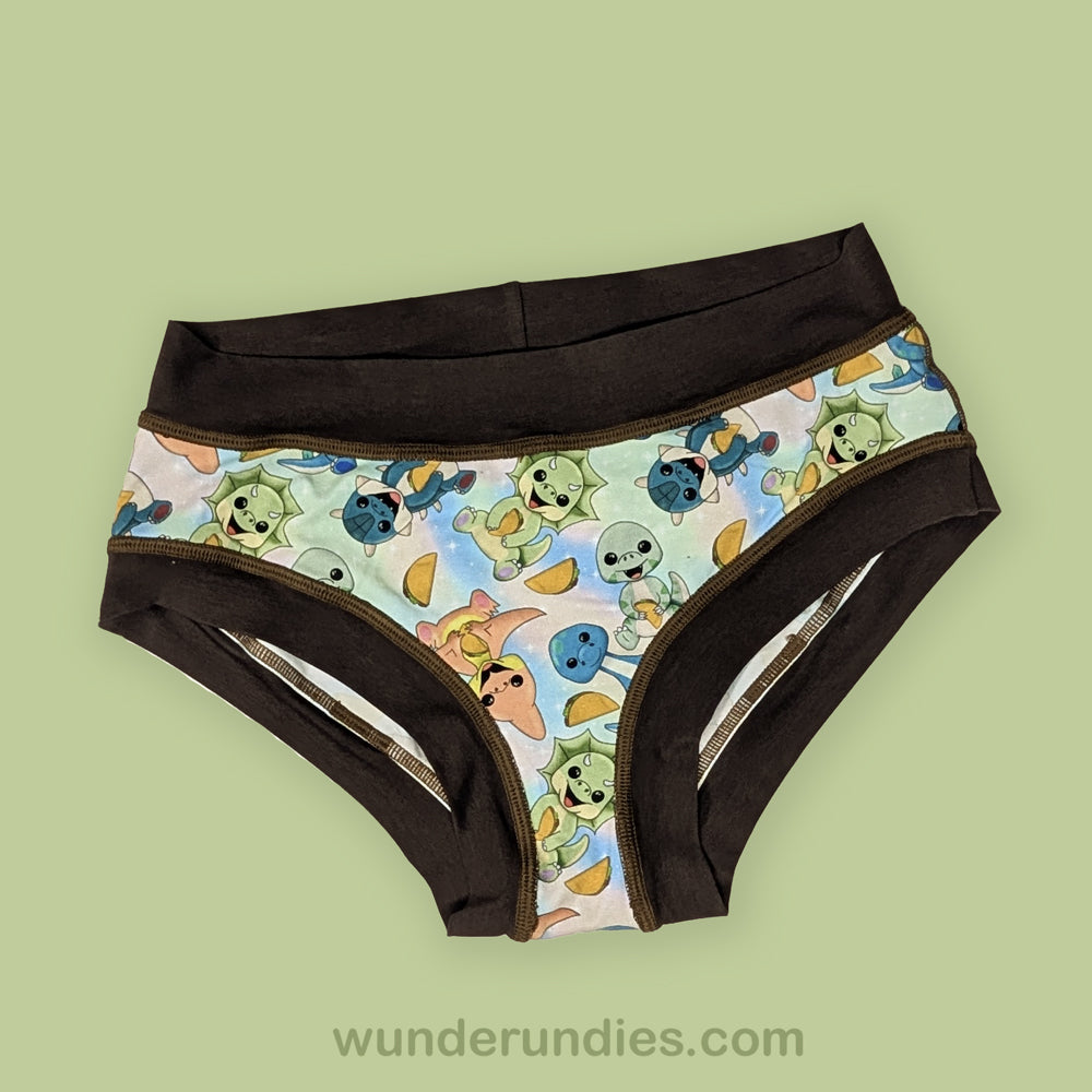Pair of adult underwear briefs with cartoon dinosaur design on a light green background
