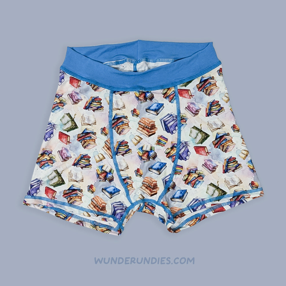 sensory friendly boxer briefs with book pattern and blue waistband on a gray background, brand 'Wunderundies' visible.