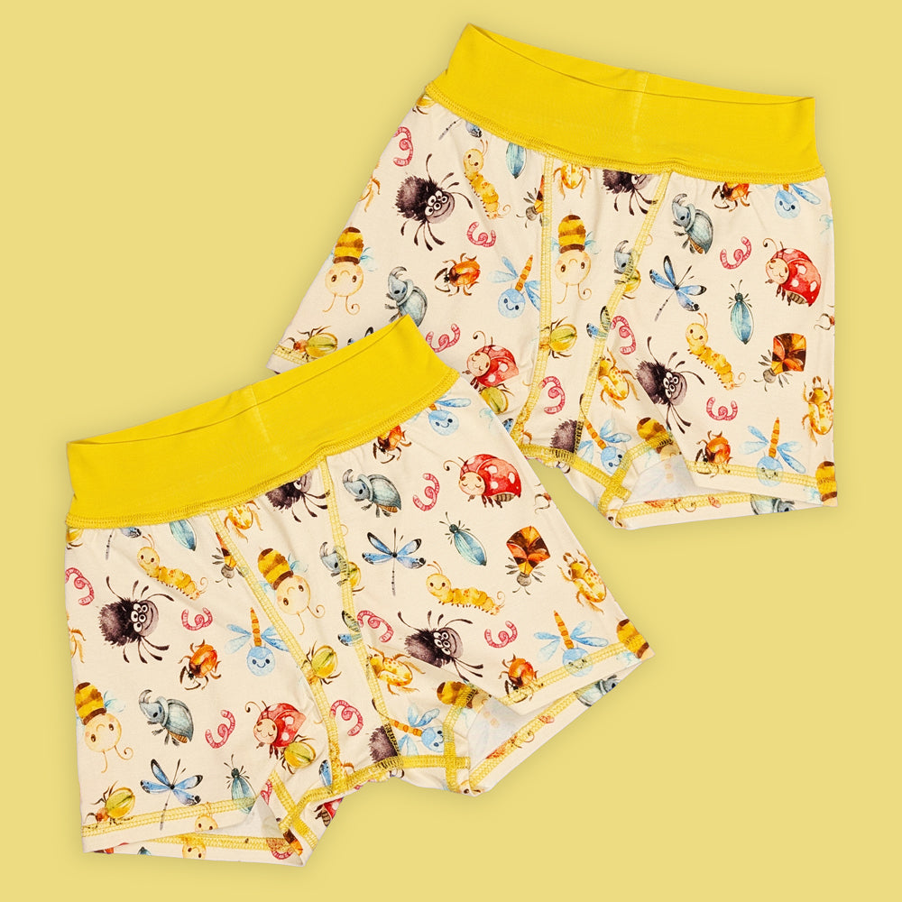 two pairs of flat seamed boxer shorts that have yellow waistbands and a cute bug print