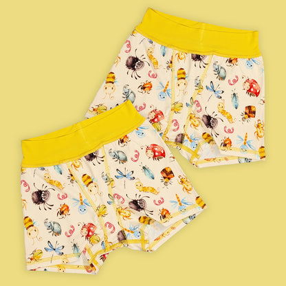 two pairs of flat seamed boxer shorts that have yellow waistbands and a cute bug print