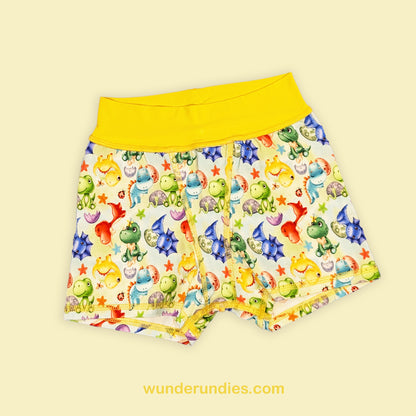 Colorful children's boxer shorts with a dinosaur pattern on a light yellow background